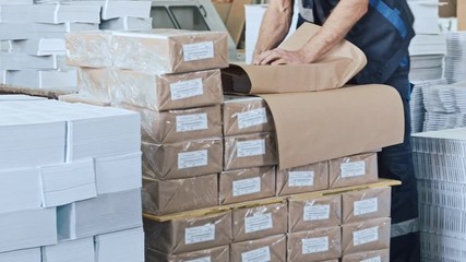 Factory worker on warehouse packing boxes for delivery - Powered by Adobe