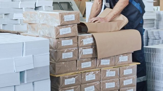 Factory worker on warehouse packing boxes for delivery