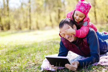 father showing game in tablet pc to his daughter in the park