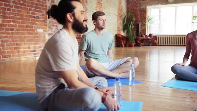 men with water resting on yoga mats in gym