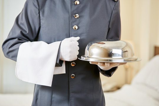 Hotel clerk serving food with cloche
