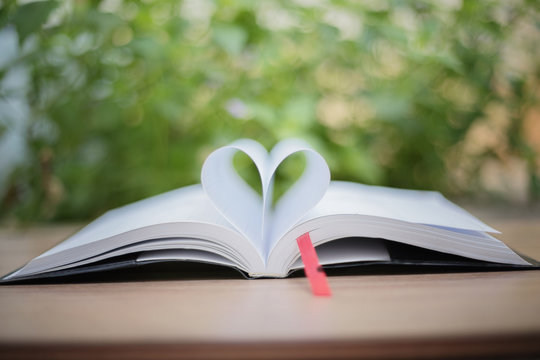 Open book on wooden table on natural background. Heart book page , blurry and soft focus