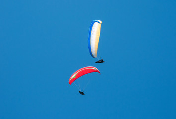 Paragliding in the blue sunny sky. One paraglider fly in summer sunny day in the clouds. Carpathians, Ukraine.