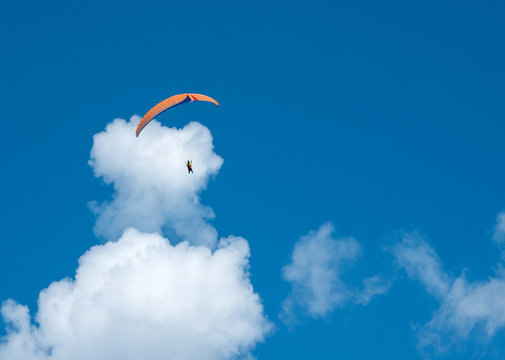 Paragliding in the blue sunny sky. One paraglider fly in summer sunny day in the clouds. Carpathians, Ukraine.