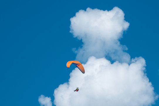 Paragliding in the blue sunny sky. One paraglider fly in summer sunny day in the clouds. Carpathians, Ukraine.