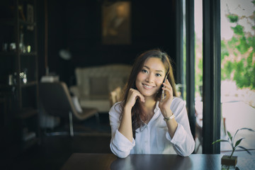 woman asian calling with cell telephone while sitting alone in coffee shop during free time