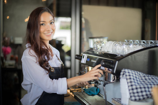 Asian women Barista  smiling and using coffee machine in coffee shop counter - Working woman small business owner food and drink cafe concept