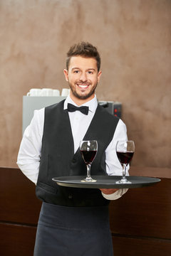 Waiter in uniform serving red wine