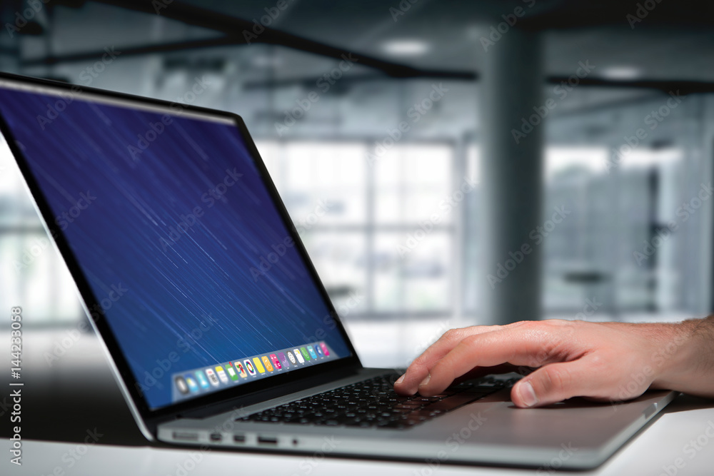 Wall mural hand typing on a keyboard of laptop with operating system screen on background
