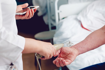 doctor with the phone treats a patient with a skin disease using the Darsonval apparatus for the treatment of dermatitis, apathic, seborrhea, eczema.