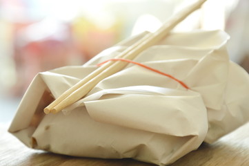 ready meal in paper packing by rubber band and wooden chopsticks