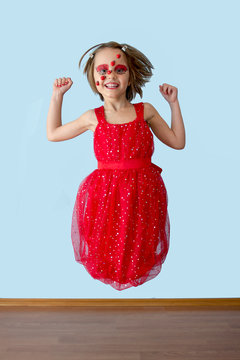 Little girl with ladybug face paint jumping