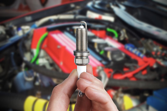 Mechanic holds a spare part spark plug in his hand. Auto part spark plug close-up.