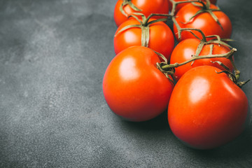 Fresh juicy tomatoes on a gray background