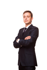 Young handsome businessman in black suit is standing straight with crossed arms, full length portrait isolated on white background