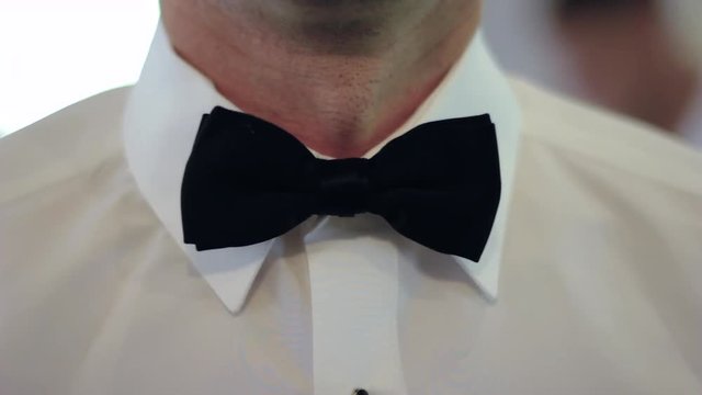 Close-up of a gentleman fixing and adjusting his black bowtie 