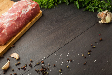 Juicy raw meat with spices, pepper, sea salt and herbs lies on a dark wooden background