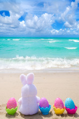 Easter bunny and color eggs on the beach