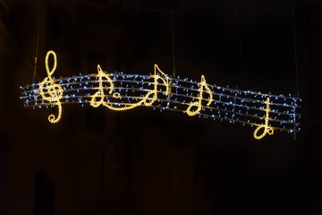 golden music notes glowing on a neon sign, isolated black background, street decoration hanging during Christmas holidays