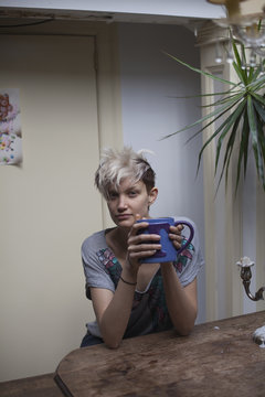 Portrait of young woman holding mug while sitting indoors