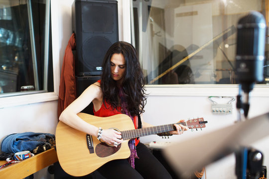 Young woman playing acoustic guitar at a recording studio