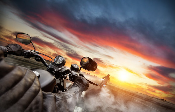 Fototapeta Motorbike riders driving towards cityscape panorama