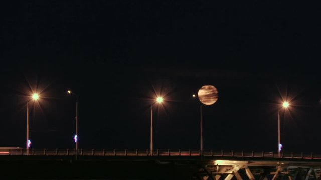 Full moon rises over the bridge. Time-lapse. Road bridge between the cities of Saratov and Engels, Russia