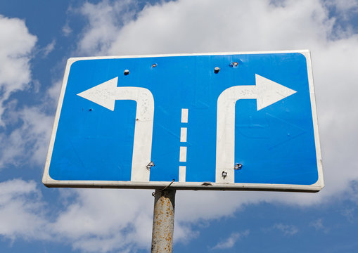 left and right turn road sign against sky