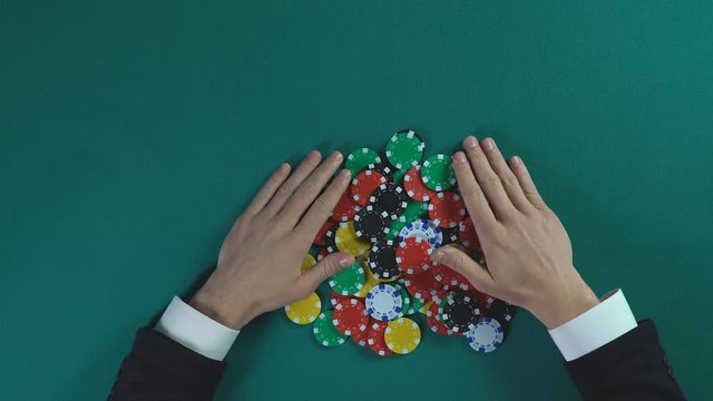 Hands of businessman taking all chips in casino, monopoly on market, top view