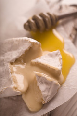 Brie cheese, slices, honey on parchment blur