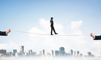 Business concept of risk support and assistance with man balancing on rope