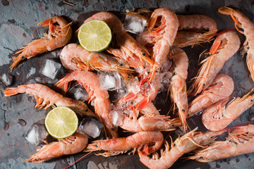 Fresh shrimps served on a gray slate with lime and ice