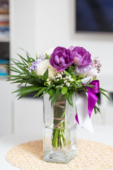 Glass vase with colorful roses and flowers in a bouquet standing on the table in the living room