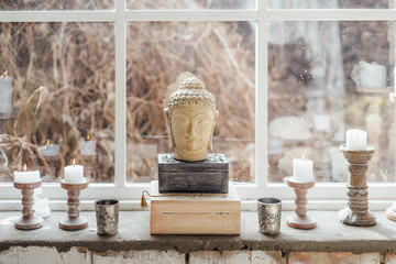 Decoration in boho style. Candles and sculpture of Buddha