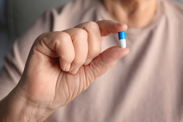 Hand of senior woman with pill, closeup