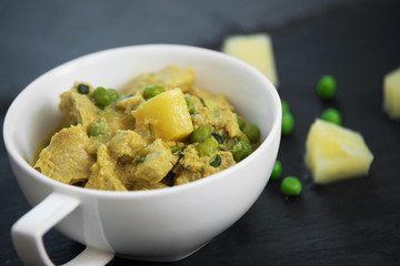 Pineapple, pea and pork stew on black stone background