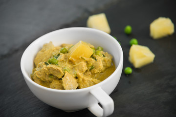 Pineapple, pea and pork stew on black stone background