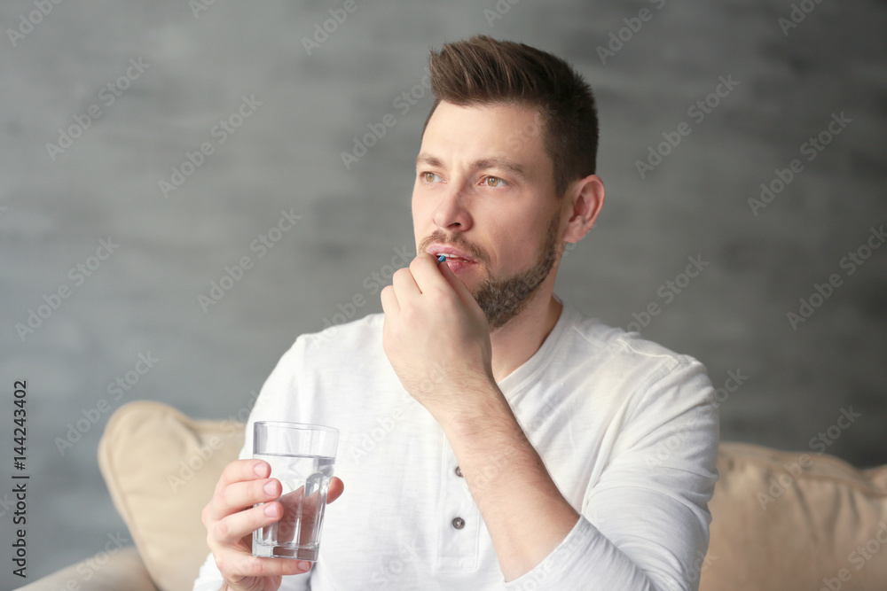 Wall mural handsome young man taking pill at home