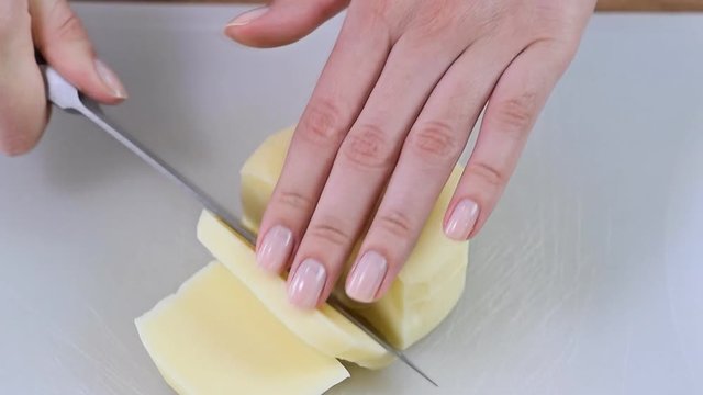 Female hands cutting mozzarella cheese on the wooden cutting board
