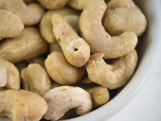 Cashew nuts in the white bowl on wooden table