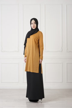 Beautiful Islamic girl in a closed, traditional Muslim dress, a studio photo in full growth