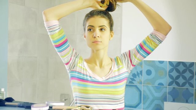 Beautiful woman pulling down long gorgeous hair in front of mirror looking camera slow motion medium shot