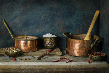 Classic still life with old copper pots placed with fresh mixed pepper,salt and dry red chili on...