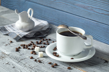 Coffee cup, beens and a jug on a background of blue boards