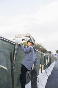 Young man climbing a fence.
