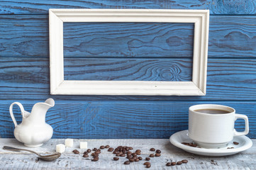White frame, coffee cup and a jug on a background of blue boards