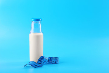 Bottle of milk with centimeter on blue background