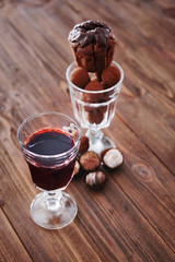 Glass of red wine and assorted sweets on wooden background