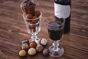 Red wine and assorted sweets on wooden background