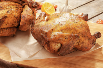 Board with roasted beer can chicken on wooden background